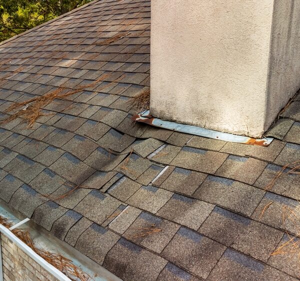 An old roof with water damage (the shingles are stained and buckling)